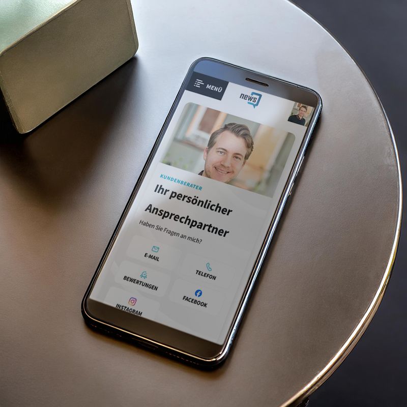 Ein Handy liegt auf einem Tisch und hat die Kontaktseite von newsQ offen. KI generiert.